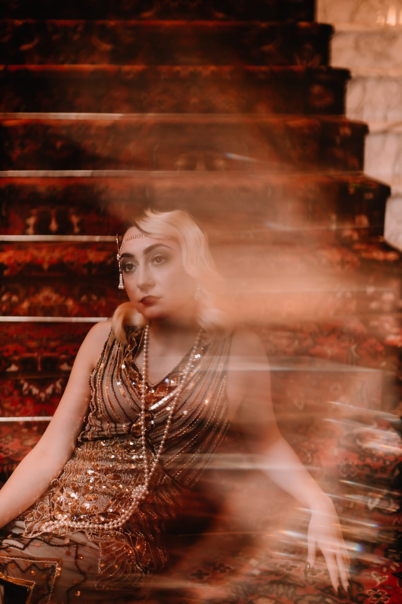 A BLONDE WOMEN IN 20'S THEMED DRESS WITH PEARLS ON A STAIR CASE IN ATLANTIC CITY SHOT BY MEERLOO PHOTOGRAPHY